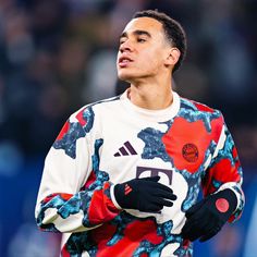 a soccer player is looking up at the sky with his hands on his hips and wearing black gloves