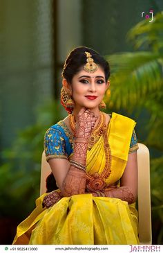 a woman in yellow and blue sitting on a chair with her hands clasped to her face