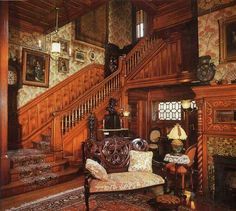 an ornately decorated living room with wood paneled walls and staircase leading up to the second floor