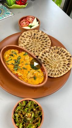 an assortment of food on a plate with bowls and spoons sitting next to it