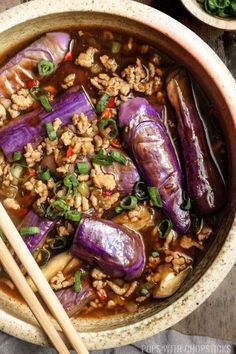 a bowl filled with rice and eggplant next to chopsticks