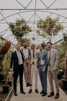 Groomsmen pose for photo in tonal neutral suits surrounded by plants Groomsmen Attire Mix And Match, Groomsmen Casual Wedding, Mixed Groomsmen Attire, Different Color Suits Groomsmen, Multicolor Groomsmen Attire, Mismatched Suits Wedding, Mix Matched Groomsmen, Formal Garden Party Attire Men, Groomsmen Ties Mismatched