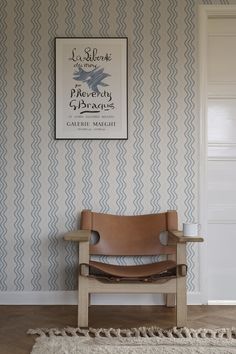 a chair sitting on top of a wooden floor next to a wall with a sign above it