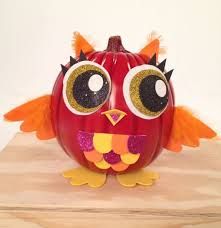 an orange pumpkin decorated to look like a bird with big eyes and large eyelashes on its head