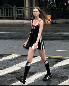 a woman in black and white is crossing the street with her hand on her hip