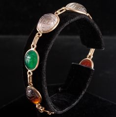 14k Yellow Gold Oval Cabochon Scarab Style Multi-Stone Bracelet 11.05gMetal Information: 14k Yellow GoldTotal Weight: 11.05gBracelet Width: 13mm - 3.5mmBracelet Length: 7.5"Stone InformationMain StoneGem Type: QuartzShape: Oval Cabochon (15.7mm x 11.75mm)Color: ClearClarity/Quality: ANumber of Stones: 1Accent StonesGem Type: QuartzShape: Oval Cabochon (13.2mm x 11.2mm / 11.8mm x 9.9mm)Color: Pink ClearClarity/Quality: ANumber of Stones: 2Accent StonesGem Type: AgateShape: Oval Cabochon (11.5mm x 9.4mm)Color: RedClarity/Quality: ANumber of Stones: 1Accent StonesGem Type: AgateShape: Oval Cabochon (11.5mm x 9.8mm)Color: Orange RedClarity/Quality: ANumber of Stones: 1Accent StonesGem Type: Tigers EyeShape: Oval Cabochon (13.7mm x 11.4mm)Color: BrownClarity/Quality: ANumber of Stones: 1Accent Oval Cabochon Bracelets For Formal Occasions, Formal Oval Intaglio Bracelet, Multi Stone, Oval Cabochon, Stone Bracelet, Color Orange, Yellow Gold, Stone, Yellow