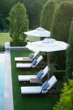 two lawn chairs and an umbrella next to a pool