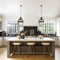 a large kitchen island with stools and lights hanging from it's ceiling above