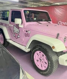 a pink jeep with hello kitty decals on it's side in a showroom