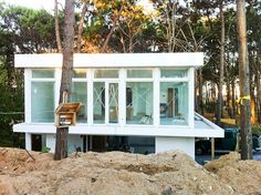 a small white house sitting on top of a pile of dirt next to some trees