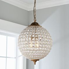 a chandelier hanging from the ceiling in a room with white walls and windows