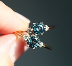 a woman's hand holding two blue and white diamond rings