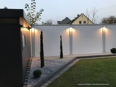 a white fence with lights on it and some bushes in the foreground next to it