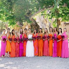 a group of women standing next to each other in long dresses and holding bouquets