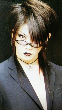 a woman with glasses on her face wearing a suit