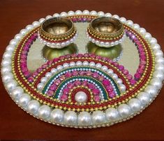 a decorative tray with two bowls and pearls on it's sides, sitting on a table