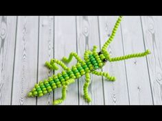 an insect made out of beads sitting on top of a wooden table