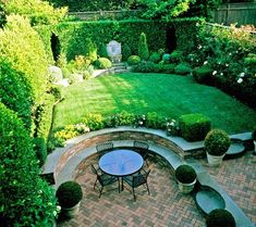 an outdoor patio with seating and table surrounded by greenery in the back yard area