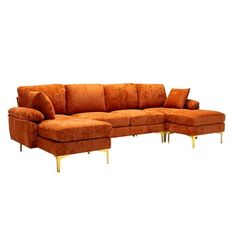 an orange sectional sofa with gold legs and pillows on the bottom, in front of a white background