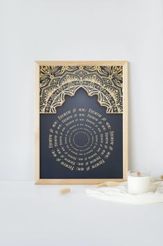 a framed poster with the words in arabic on it next to a cup and saucer