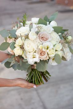 a bridal bouquet being held by someone's hand