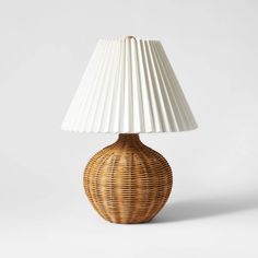 a wicker table lamp with a white shade on the top, and a wooden base