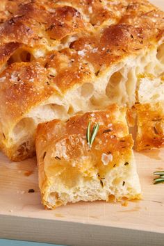 a piece of bread that has been cut in half on a cutting board with rosemary sprigs