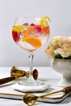 a glass filled with liquid and garnished with orange slices, lemons, and flowers