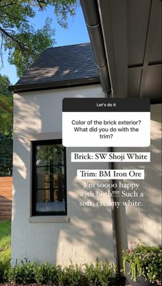 a white house with black shingles and the words brick s w stop white trim