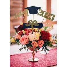 a bouquet of flowers in a vase with a graduation hat on top that says happy birthday