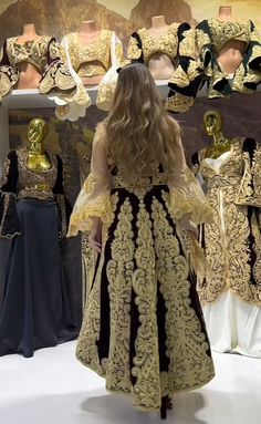 a woman standing in front of mannequins dressed in gold and black clothing