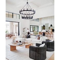 a living room filled with lots of furniture and a chandelier hanging from the ceiling