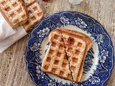 two waffles on a blue and white plate next to some strawberries,