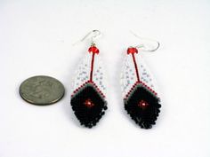 a pair of beaded earrings sitting next to a penny