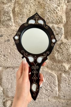 a person holding a mirror in front of a stone wall with white stones on it