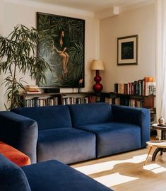 a living room filled with blue couches next to a book shelf full of books