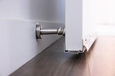 a close up of a door handle on a wooden floor with white walls and wood floors