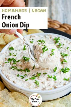 a spoon dipping dip into a bowl of homemade vegan onion dip surrounded by tortilla chips