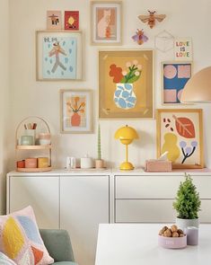 a living room with pictures on the wall and furniture in front of it's white table