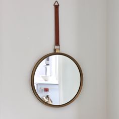 a round mirror hanging on the wall above a sink in a room with white walls