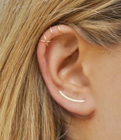 a woman's ear is shown with two thin bar earrings