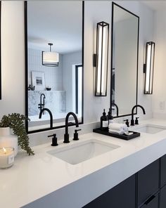 a bathroom with two sinks and three mirrors on the wall above them is lit by candles