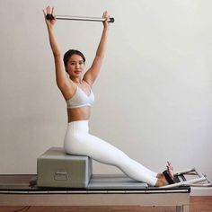 a woman in white is doing exercises on an exercise mat with a pull - up bar