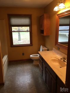 a bathroom with a toilet, sink and window in it's center area is shown