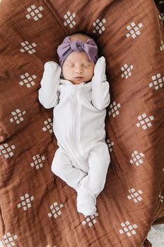 a baby is sleeping on a brown blanket