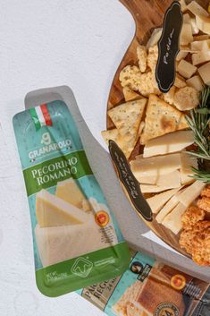 cheese and crackers on a wooden plate next to a bag of gravy