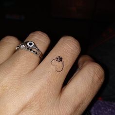 a person's hand with two rings on it and an apple tattoo on the middle finger