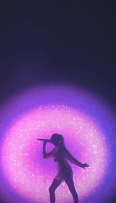 a woman standing in front of a purple light with her arms out to the side