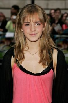 a young woman with long hair and pink top posing for the camera in front of a crowd