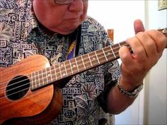 an older man is playing the ukulele with his fingers while wearing a hawaiian shirt